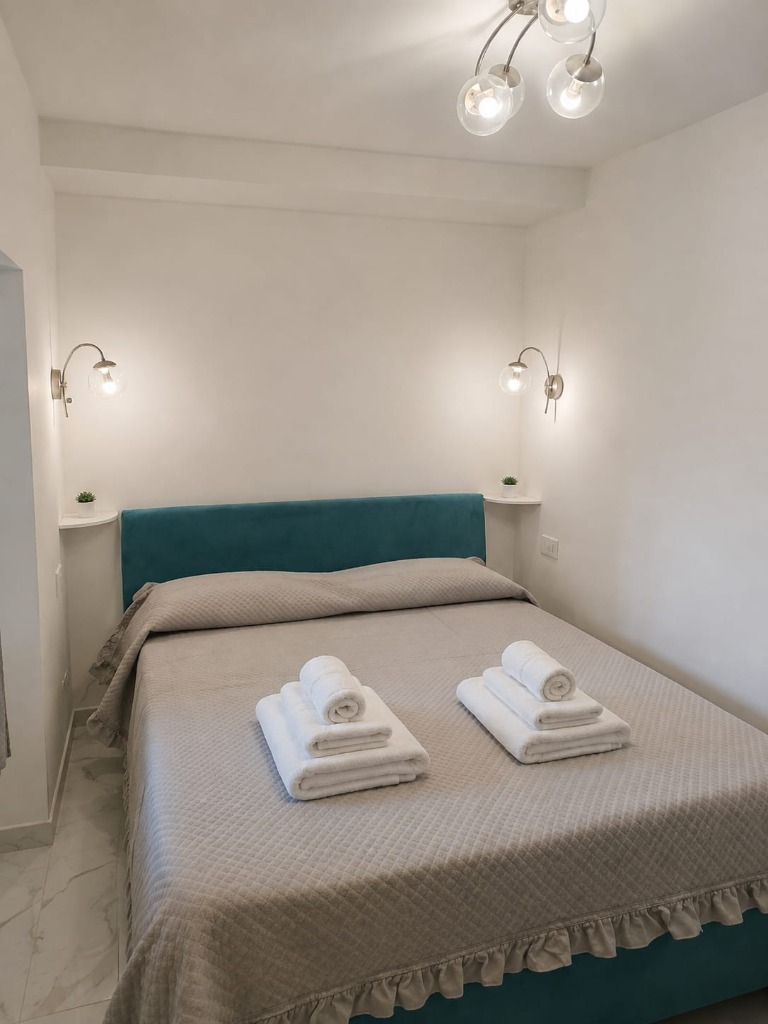 Camera da letto matrimoniale con testiera verde petrolio e luci da lettura